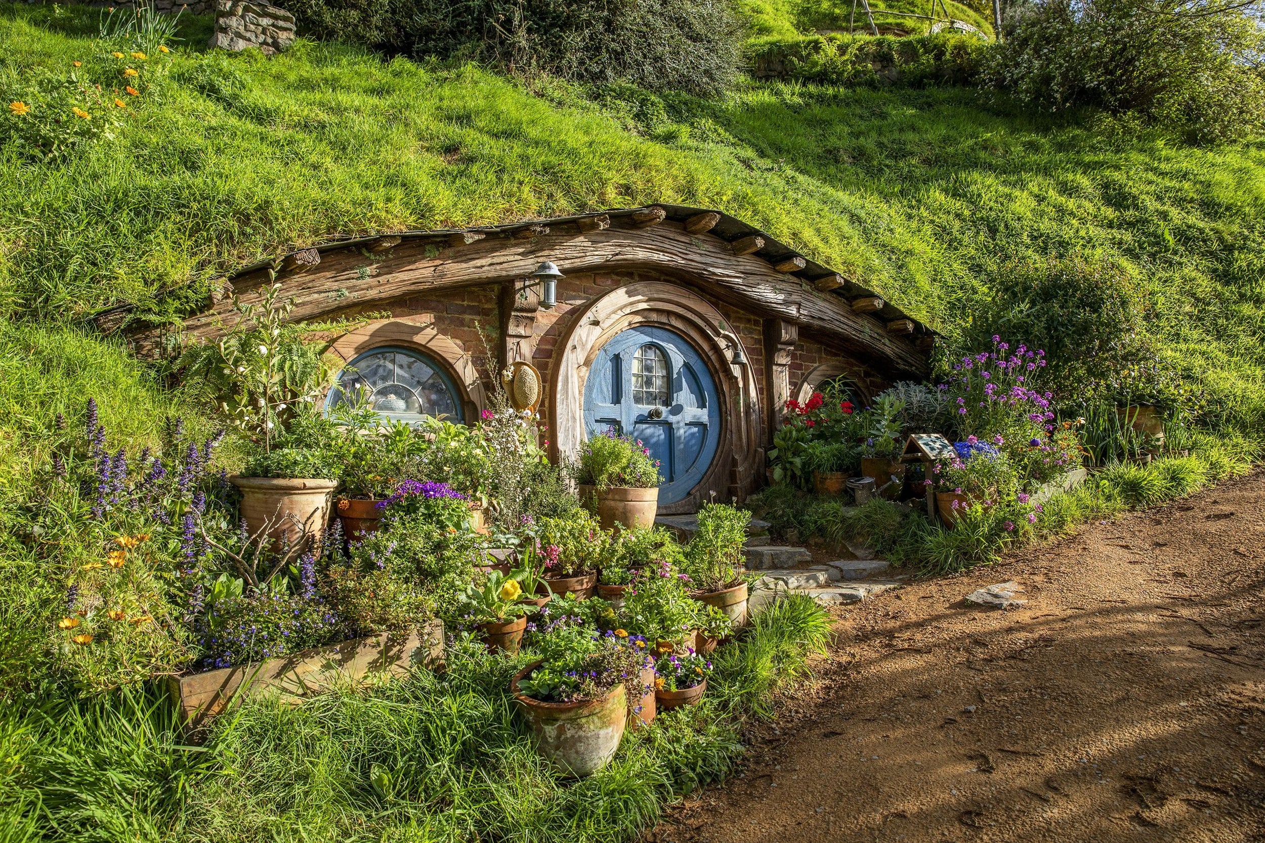 A hobbit hole with a round door in the green hills of Hobbiton, Waikato