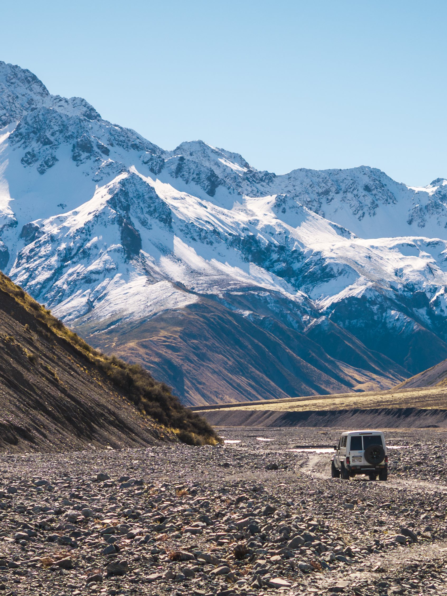 A four-wheel drive on a braided riverbed below the snowline, Canterbury high country