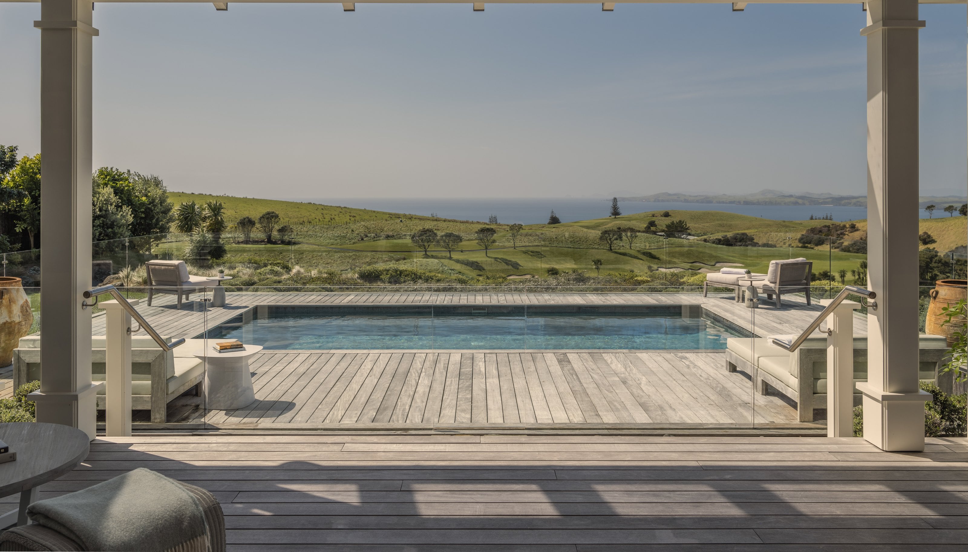 The pool terrace at Kauri Cliffs, decking and loungers above the fairways and the sea