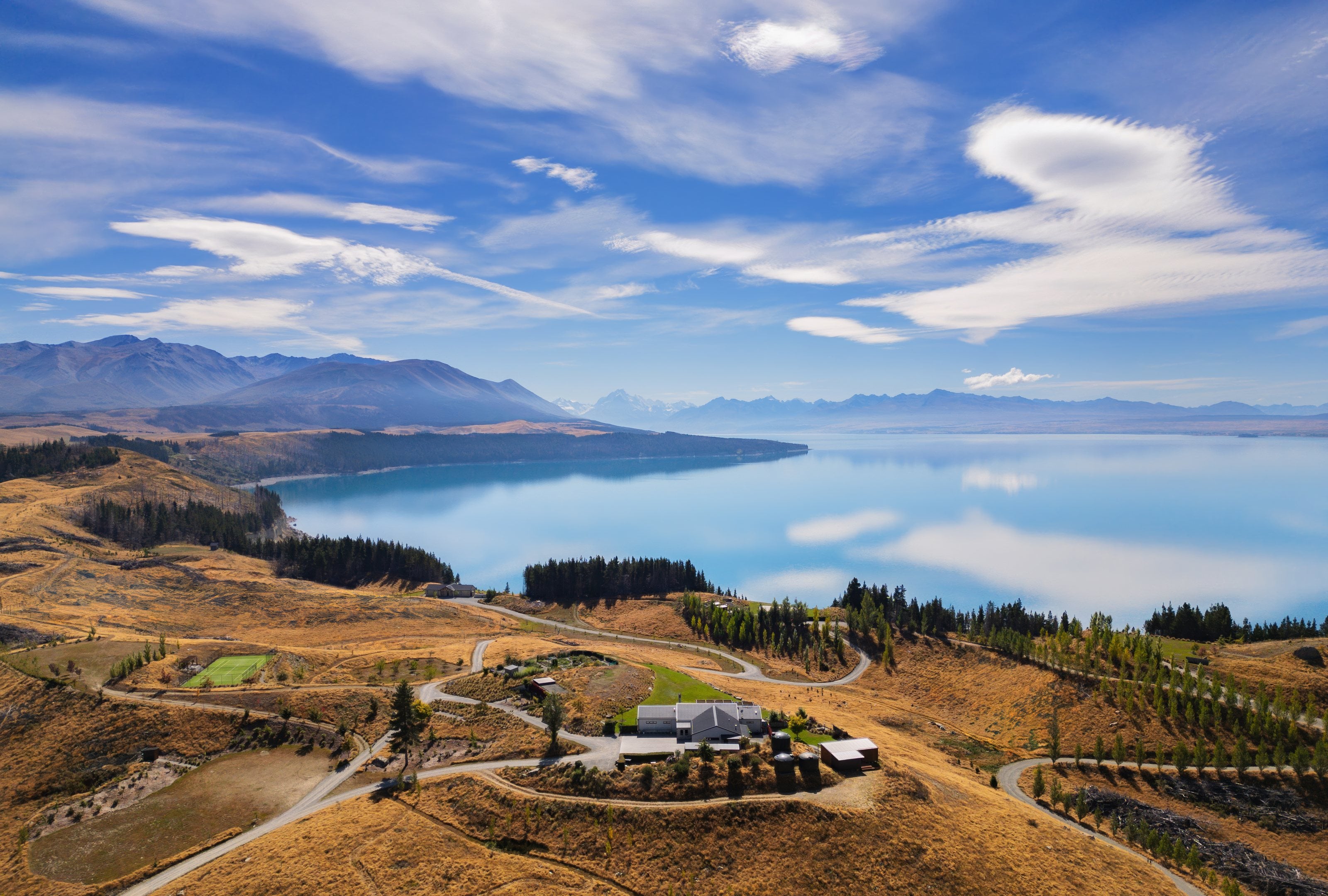 A lodge on the tussock hills above Lake Pukaki, Aoraki / Mount Cook in the distance